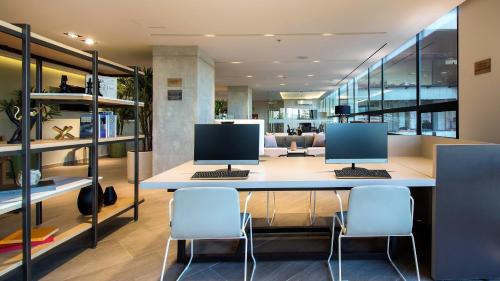an office with two monitors on a desk with chairs at Staybridge Suites - Guadalajara Novena by IHG in Guadalajara