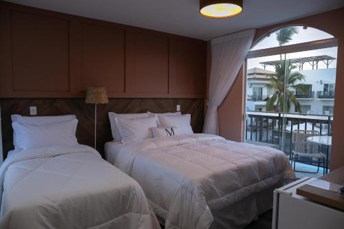 two beds in a bedroom with a balcony at Mero Hotel Boutique in Barra Grande