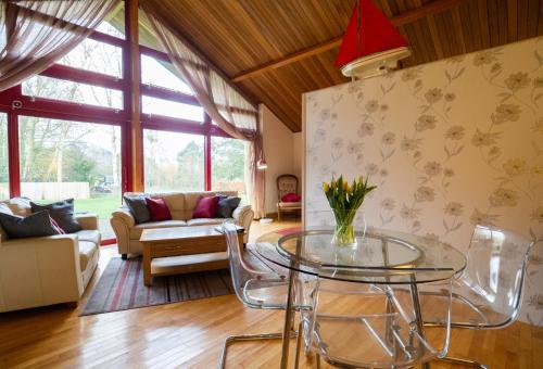 a living room with a glass table and a couch at Surlingham Lodge Studio Large Family Cottage in Norwich