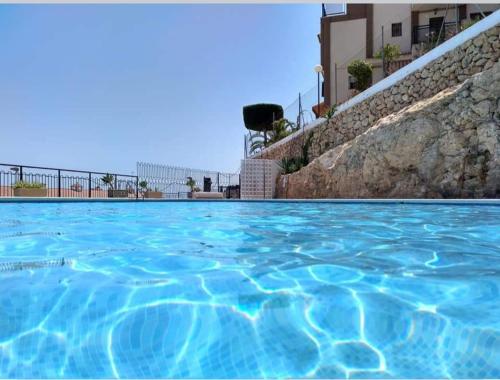 basen z niebieską wodą przed budynkiem w obiekcie MEDITERRANEAN BEACH APARTMENT 180º SEA & ISLAND VIEWS w mieście Santa Pola