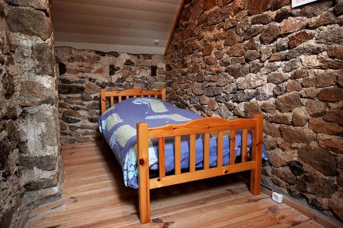 - une chambre avec un lit en bois dans un mur en pierre dans l'établissement Gite Four a Pain Charlannes, à Hautefage
