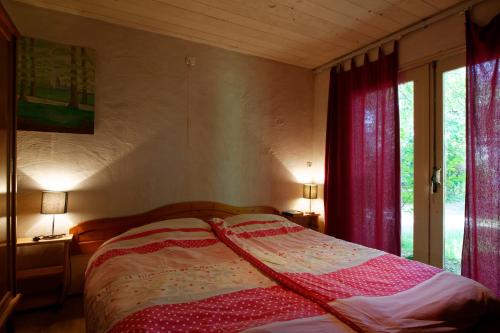 - une chambre avec un lit doté de rideaux rouges et d'une fenêtre dans l'établissement Gite Four a Pain Charlannes, à Hautefage
