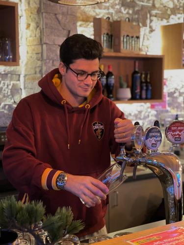 a man is pouring wine into a glass at Freeride Hostel in Les Crosets