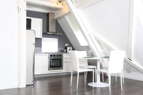 a kitchen with white cabinets and a table and chairs at My Sweet Homes - La Grenouillère HYPERCENTRE in Colmar