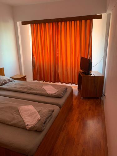 een slaapkamer met 2 bedden en een oranje gordijn bij HOTEL modern / Imobiliare Garcea Titu in Titu