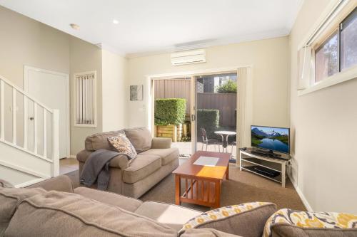 a living room with a couch and a tv at Newcastle Short Stay Accommodation - Birmingham Garden Townhouses in Newcastle