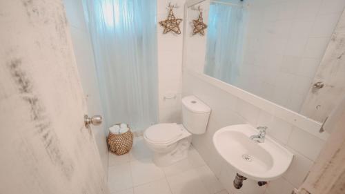 a white bathroom with a toilet and a sink at Marbelo Coveñas by Bernalo Hotels in Coveñas