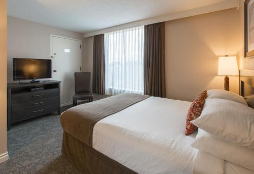 a hotel room with a bed and a flat screen tv at The Embassy Inn in Victoria