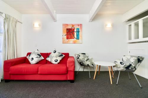 a living room with a red couch and a table at Gables Lakefront Resort in Taupo