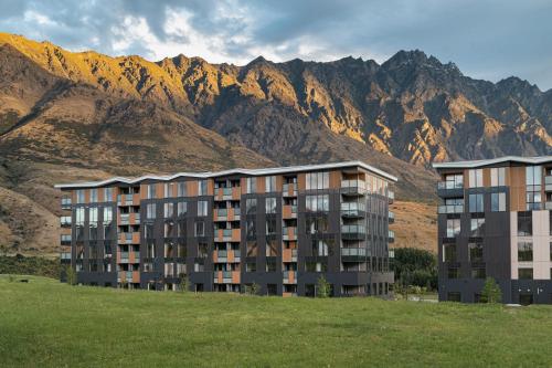 an apartment building with mountains in the background at La Quinta Queenstown in Queenstown
