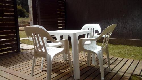 4 sillas blancas y una mesa en una cubierta en Entre Gaviotas en Las Gaviotas