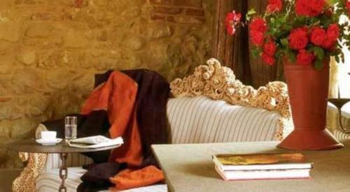 a couch with a table and a vase with flowers at Albergo l'Ostelliere - Villa Sparina Resort in Gavi