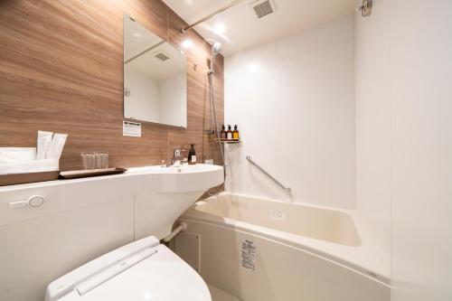 a bathroom with a toilet and a sink and a mirror at KOKO HOTEL Sapporo Odori in Sapporo