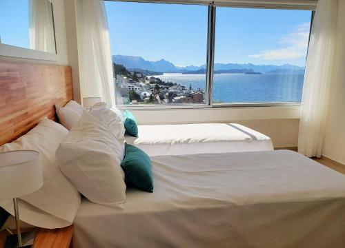 a bedroom with two beds and a large window at CONDOR STUDIO BARILOCHE in San Carlos de Bariloche