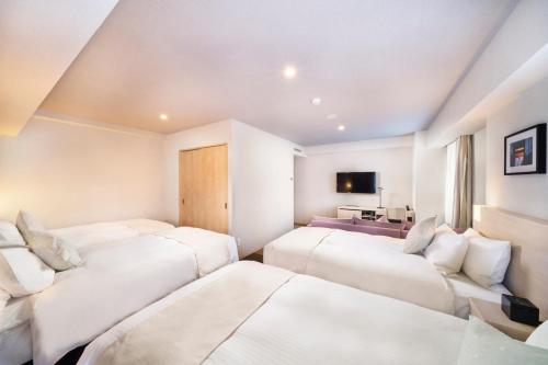 a room with three beds and a television at KOKO HOTEL Sapporo Odori in Sapporo