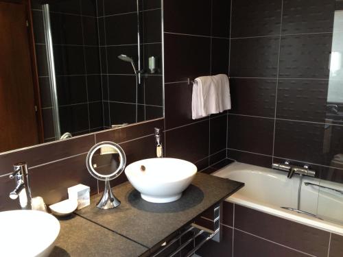 a bathroom with a sink and a tub and a mirror at Hotel Restaurant L'Ami Fritz in Ottrott