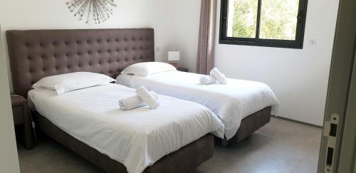 une chambre avec deux lits avec draps blancs et oreillers dans l'établissement Villa Tinuta 8 pers piscine chauffée 5 min plage en voiture, à Sainte-Lucie de Porto-Vecchio