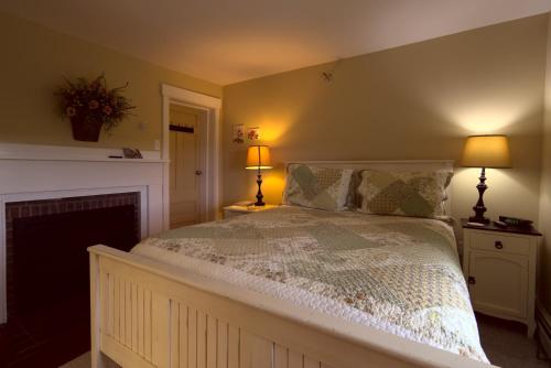 a bedroom with a bed with two lamps and a fireplace at Ballard House Inn in Meredith