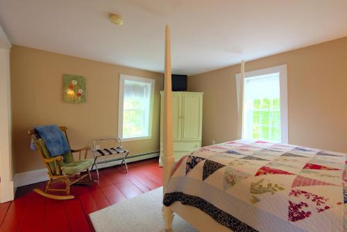 a bedroom with a bed and a chair and windows at Ballard House Inn in Meredith