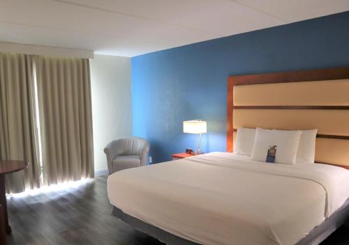 een hotelkamer met een groot bed en een stoel bij Baymont by Wyndham Norcross Atlanta in Norcross