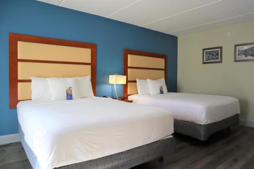 two beds in a hotel room with blue walls at Baymont by Wyndham Norcross Atlanta in Norcross