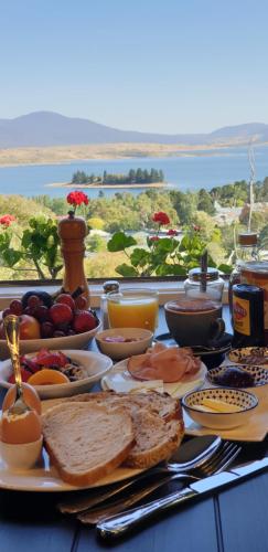 a table with breakfast food on a table with a view at Troldhaugen Lodge - Adults Only in Jindabyne