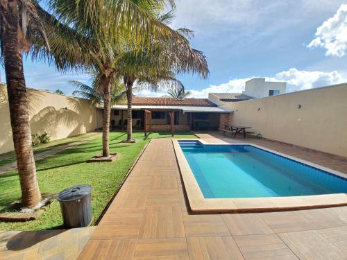 a swimming pool with palm trees next to a house at Casa para Temporada em Chapada dos Guimarães in Chapada dos Guimarães