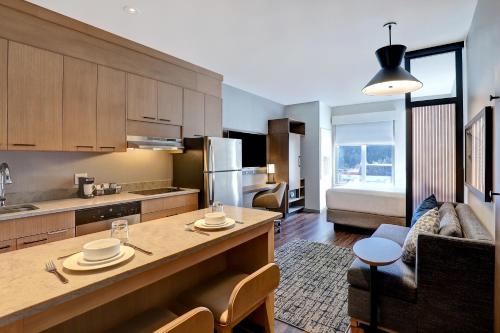 a kitchen and living room with a table and a couch at Hyatt Place Prince George in Prince George