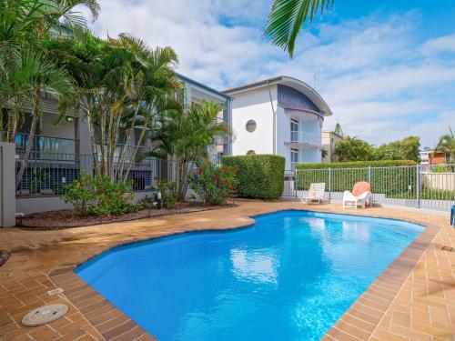 a swimming pool in front of a house with palm trees at Blue Pacific 2 in Yamba