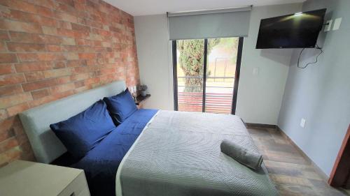1 dormitorio con 1 cama con almohadas azules y pared de ladrillo en R08 LUXURY STUDIO RAISE a 5 MIN DEL ITESM R08, en Ciudad de México