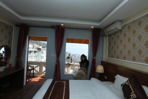 a woman sitting in a window in a hotel room at Sapa Unique Hotel in Sa Pa