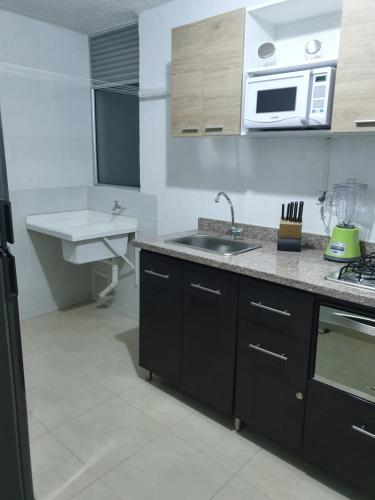a kitchen with a sink and a microwave at Apartamento Completo, Perfecto para tus viajes in Cúcuta