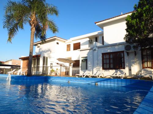 una piscina frente a una casa con palmeras en Casa Piedra Hotel en Villa Carlos Paz