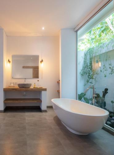 a bath tub in a bathroom with a large window at Villa Passiondream including private cook & butlerservice in Jasri