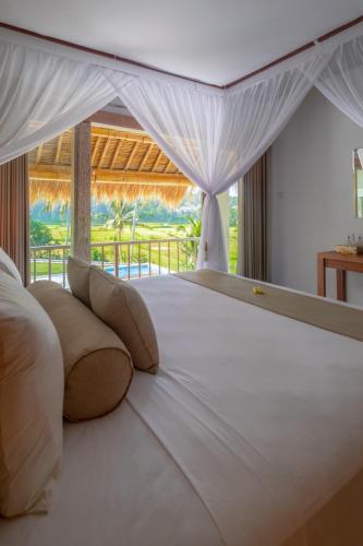 a bedroom with a large white bed with a window at Villa Passiondream including private cook & butlerservice in Jasri