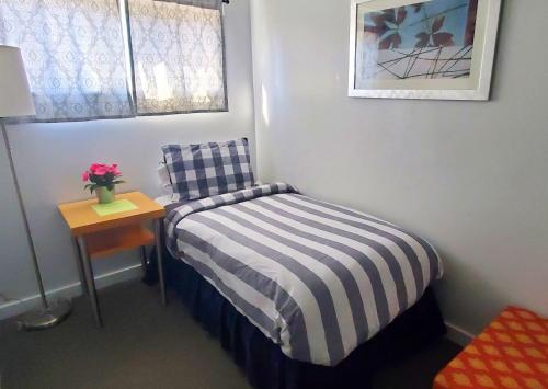 a small bedroom with a bed and a table with a lamp at Gannett Peak Lodge in Pinedale