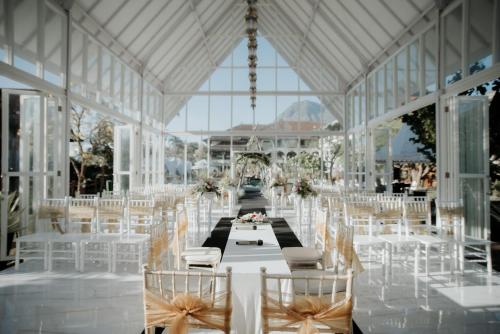 a banquet hall with white chairs and a table with flowers at Royal Orchids Garden Hotel & Condominium in Batu