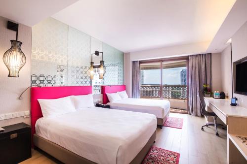a hotel room with two beds and a television at Village Hotel Katong by Far East Hospitality in Singapore