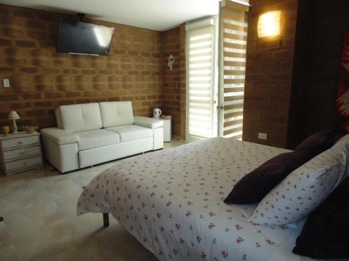 a bedroom with a white bed and a white couch at Bella Tierra Hotel Boutique in Tibasosa
