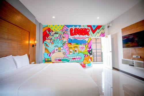 a bedroom with a white bed and a colorful wall at Smart Hotel in Lam Luk Ka