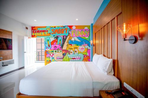 a bedroom with a white bed with a painting on the wall at Smart Hotel in Lam Luk Ka