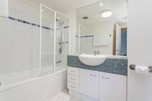 a white bathroom with a sink and a shower at Republic Apartments Brisbane City in Brisbane