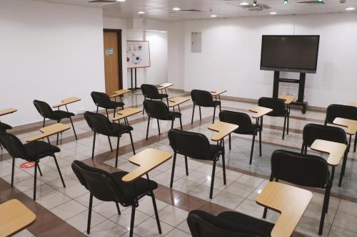 a classroom with desks and chairs and a projection screen at Spark Residence Hotel in Sharjah