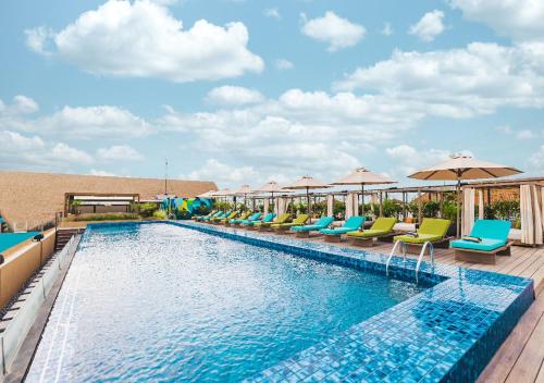 een zwembad met stoelen en parasols op een resort bij MAMAKA by Ovolo in Kuta