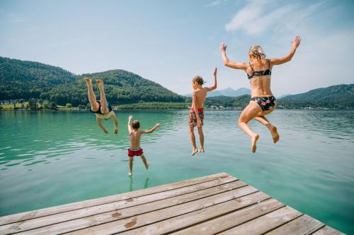 a group of people jumping off a dock into a lake at Landhaus Klopein in Sankt Kanzian