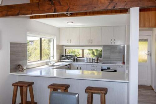 a kitchen with white cabinets and a counter with stools at Mountain Views, Nice Spot Newly renovated in Lake Tekapo