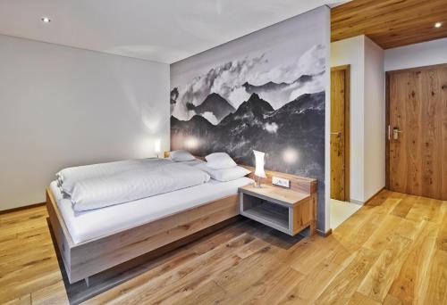 a bedroom with a large bed and a wall mural at Sporthotel Silvretta Montafon in Gaschurn