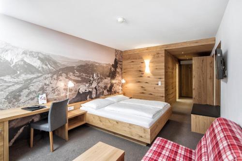 a bedroom with a bed and a desk with a computer at Sporthotel Silvretta Montafon in Gaschurn