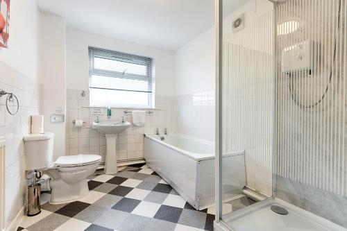 a bathroom with a tub and a toilet and a sink at Perfect Base to Stay in Swansea - TV in every Bedroom! in Swansea