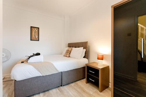a bedroom with a large bed and a night stand at 3BR Home in Morriston, Swansea in Swansea